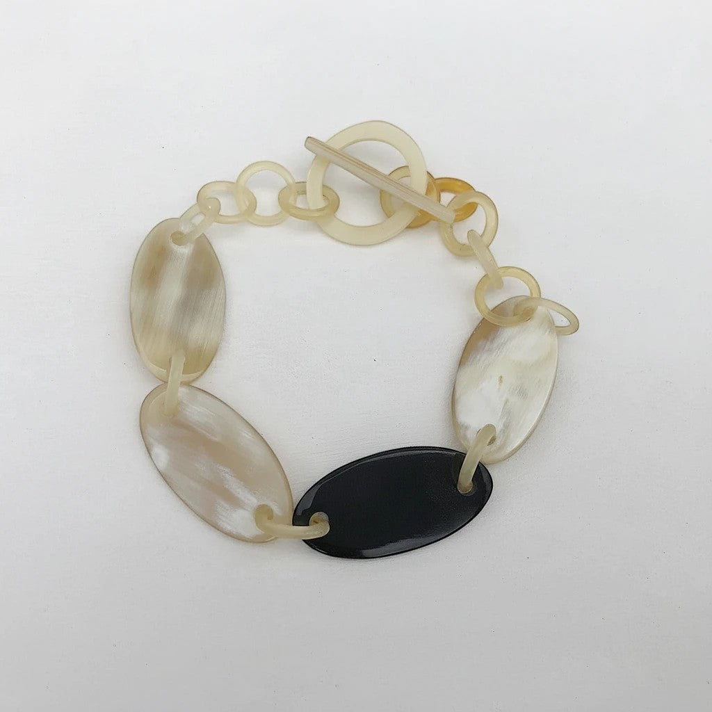 NICAY Hornarmband mit Toggle-Verschluss, ovalen Horn-Elementen in Beige und einem schwarzen Element.
